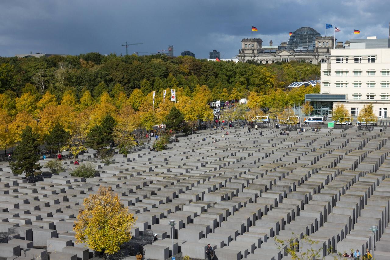 Das Denkmal für die ermordeten Juden in Berlin mit hunderten grauen Beton-Stehlen, im Hintergrund sieht man das Bundestgsgebäude Das Denkmal für die ermordeten Juden in Berlin mit hunderten grauen Beton-Stehlen, im Hintergrund sieht man das Bundestgsgebäude