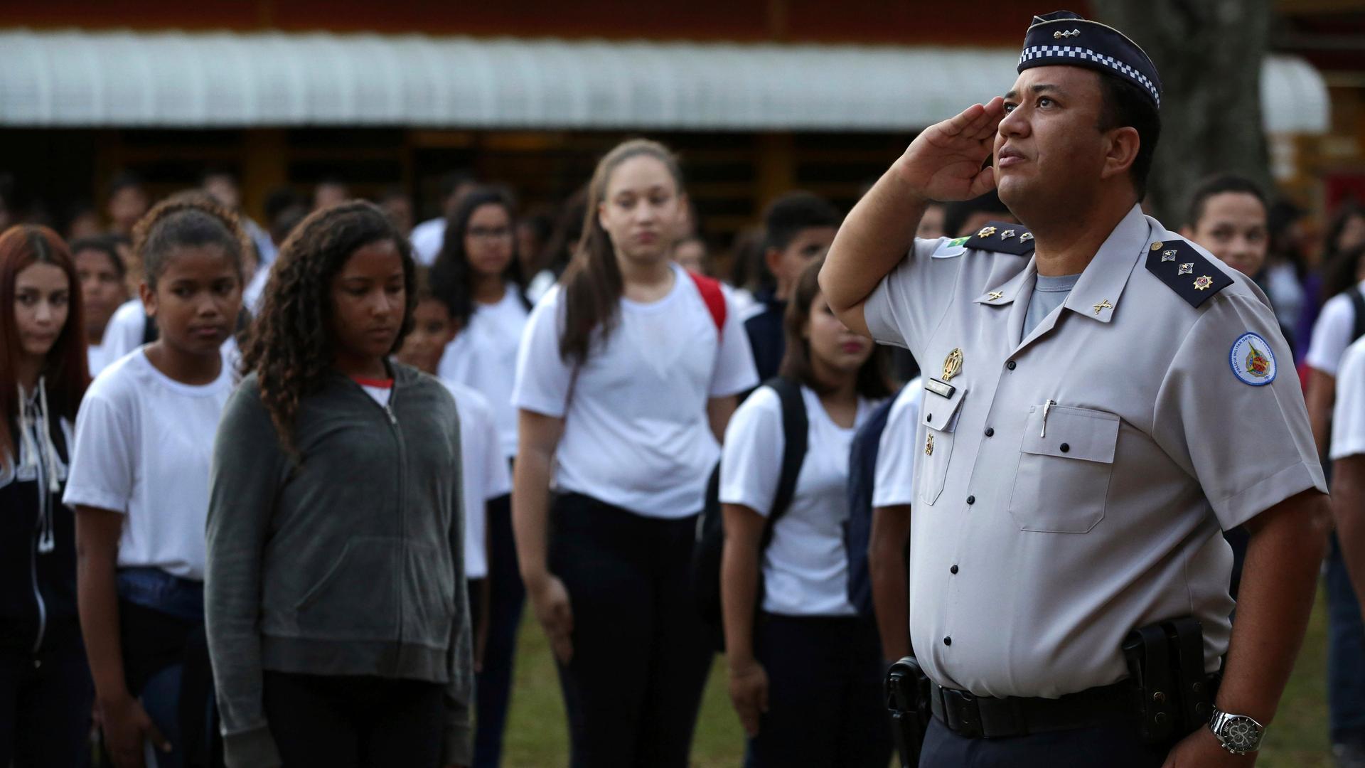 Schülerinnen und Schüler stehen stramm vor einem Offizier in Uniform, der in Richtung Fahne (nicht im Bild) salutiert Schülerinnen und Schüler stehen stramm vor einem Offizier in Uniform, der in Richtung Fahne (nicht im Bild) salutiert