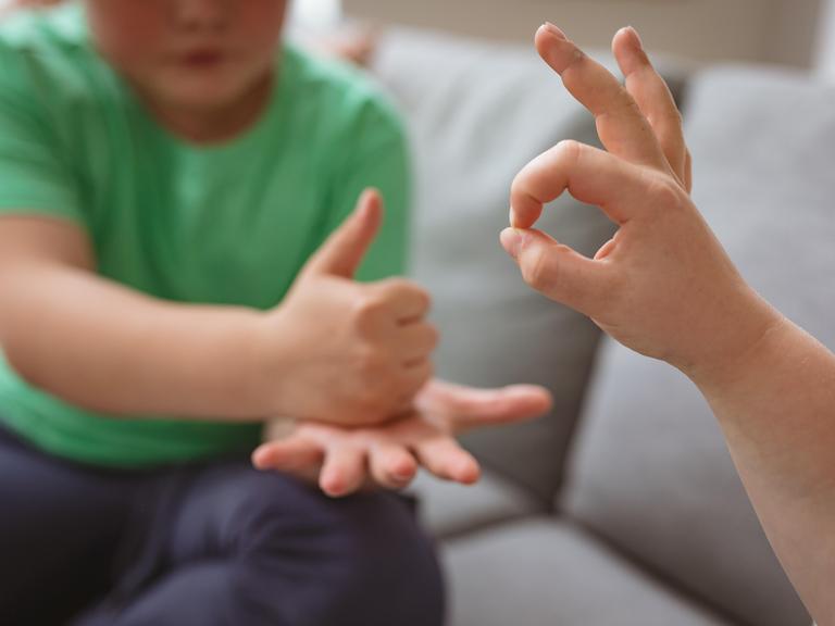Zwei Jungen benutzen Gebärdensprache, um sich zu unterhalten.
