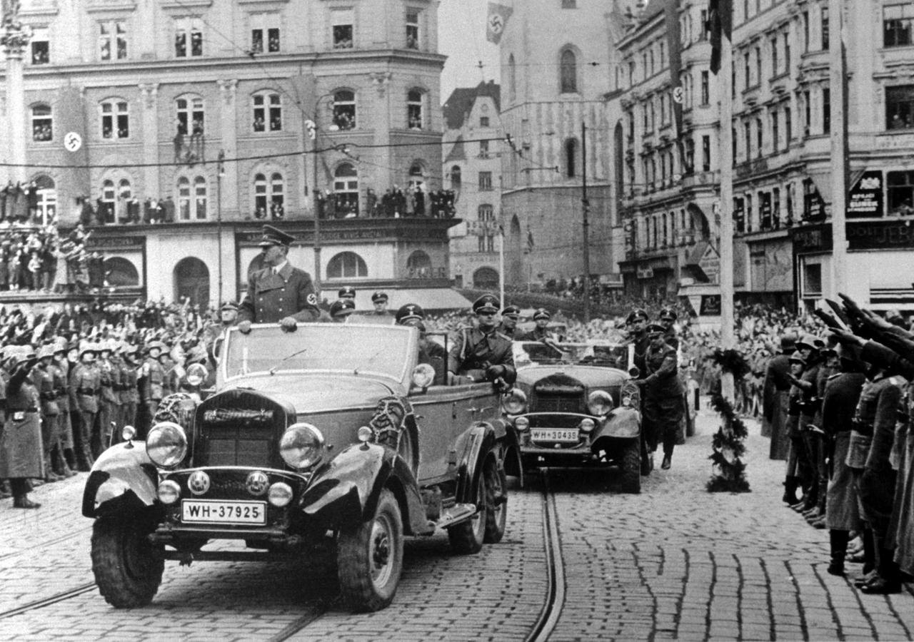 Historisches Foto von Adolf Hitler, der in einem offenen Wagen stehend durch Brünn fährt. Menschenmengen haben sich versammelt. Historisches Foto von Adolf Hitler, der in einem offenen Wagen stehend durch Brünn fährt. Menschenmengen haben sich versammelt.
