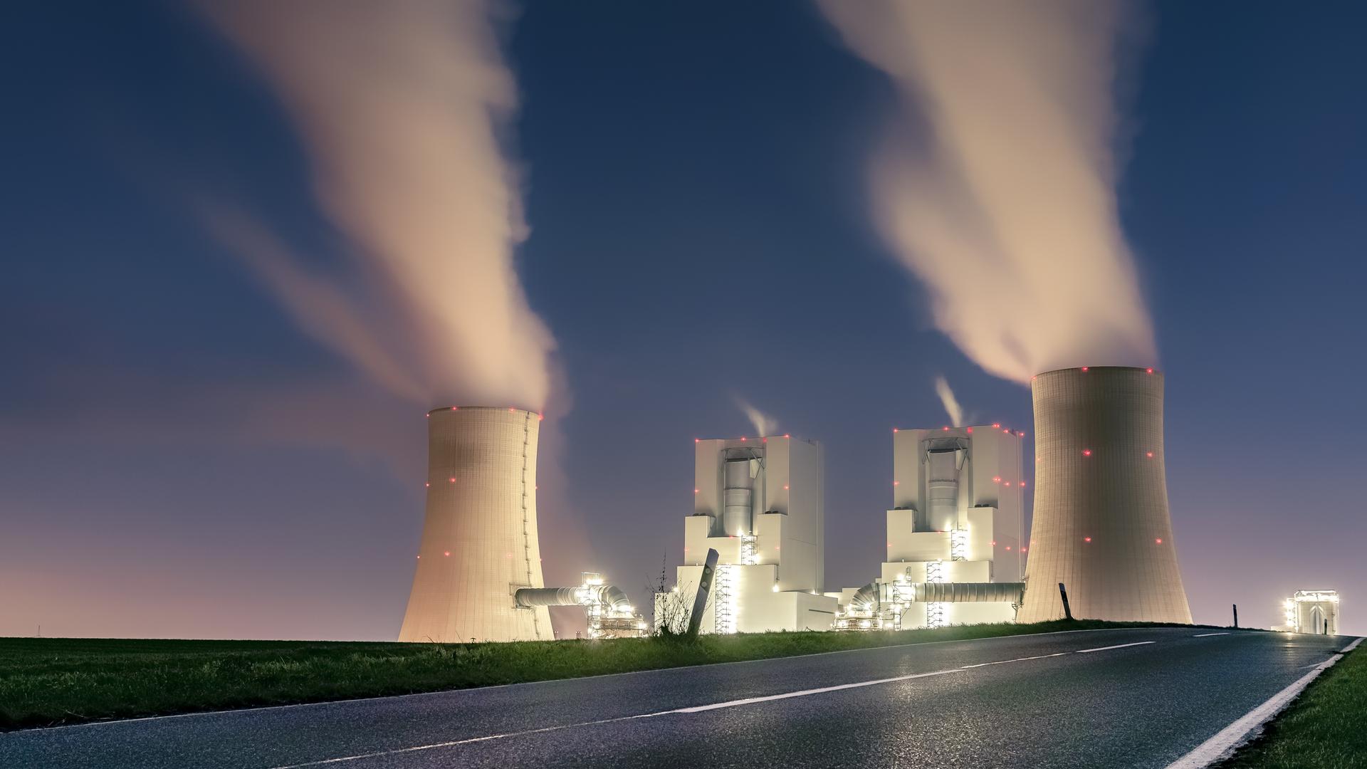 Zu sehen ist ein beleuchtetes Kohlekraftwerk in der Dunkelheit. Zu sehen ist ein beleuchtetes Kohlekraftwerk in der Dunkelheit.