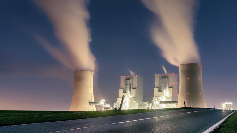 Zu sehen ist ein beleuchtetes Kohlekraftwerk in der Dunkelheit. Zu sehen ist ein beleuchtetes Kohlekraftwerk in der Dunkelheit.