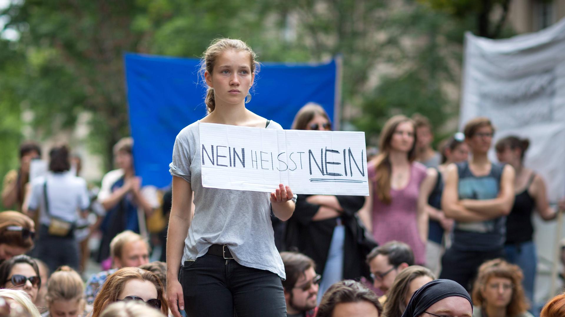 Eine junge Frau hält auf einer Kundgebung ein Transparent mit der Aufschrift "Nein heisst Nein" in ihrer Hand.