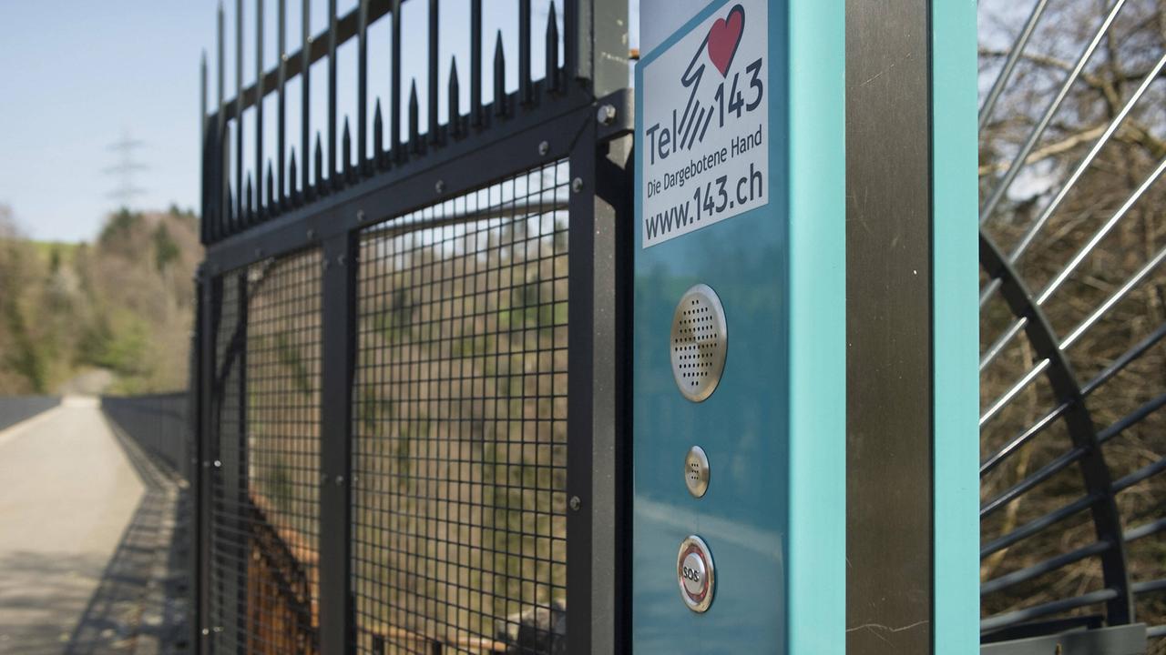 Notruf-Sprechanlage zum Telefonseelsorgedienst "Die dargebotene Hand - Telefon 143" neben dem Absperrgitter am Aufgang zur zweiten Lorzetobelbrücke am Mittwoch (21.04.10) oberhalb von Baar. Der 1910 fertiggestellte und heute nur noch dem Fussgängerverkehr dienende Viadukt mit einer maximalen Pfeilerhöhe von knapp 60 Metern wird gehäuft von lebensmüden Personen zum Freitod durch den Sprung in das Tobel gewählt. Um die Suizide zu vermindern, brachten die Behörden auf der ganzen Länge von 187 Metern hohe Zäune an und installierten an den Brückenköpfen Notrufsäulen. Notruf-Sprechanlage zum Telefonseelsorgedienst "Die dargebotene Hand - Telefon 143" neben dem Absperrgitter am Aufgang zur zweiten Lorzetobelbrücke am Mittwoch (21.04.10) oberhalb von Baar. Der 1910 fertiggestellte und heute nur noch dem Fussgängerverkehr dienende Viadukt mit einer maximalen Pfeilerhöhe von knapp 60 Metern wird gehäuft von lebensmüden Personen zum Freitod durch den Sprung in das Tobel gewählt. Um die Suizide zu vermindern, brachten die Behörden auf der ganzen Länge von 187 Metern hohe Zäune an und installierten an den Brückenköpfen Notrufsäulen.