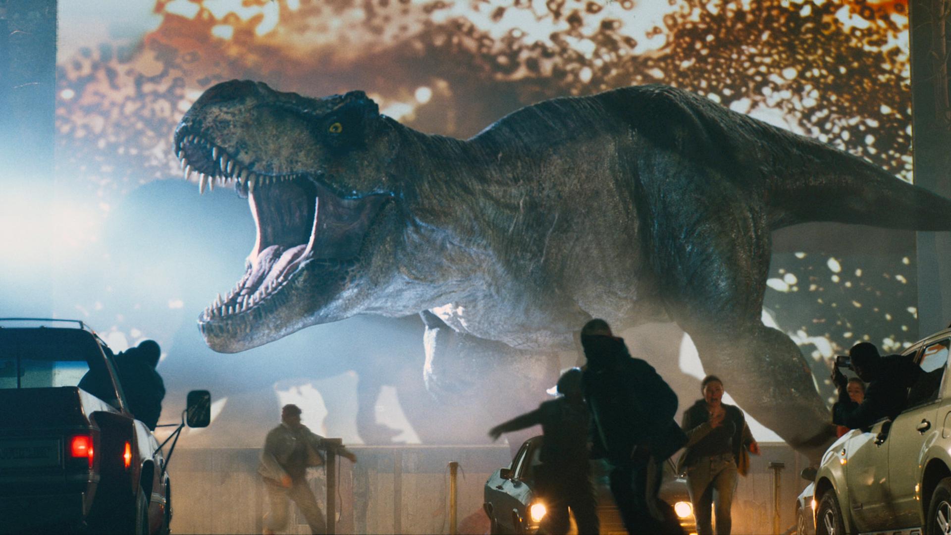 Filmszene aus "Jurassic World 3", ein T-Rex Dinosaurier setzt die Menschen in einem Autokino in Angst und Schrecken. Filmszene aus "Jurassic World 3", ein T-Rex Dinosaurier setzt die Menschen in einem Autokino in Angst und Schrecken.