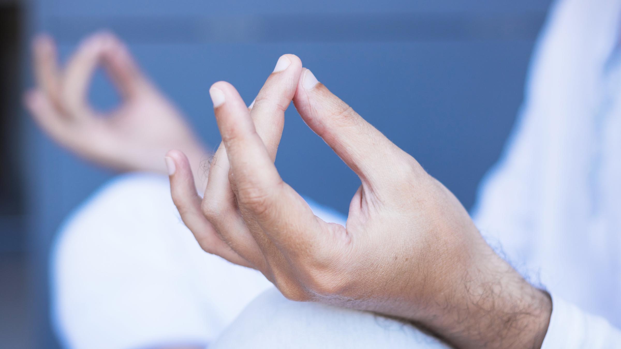 Hände liegen entspannt auf den Knien beim Schneidersitz.