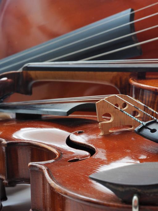 Unterschiedliche Streichinstrumente wie Violine, Bratsche und Violoncello liegen nah beieinander.