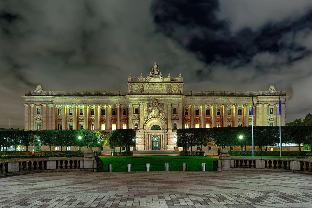 Ein monumentaler Bau mit Seitenflügeln vor einem Park im Licht der Scheinwerfer bei Nacht. Ein monumentaler Bau mit Seitenflügeln vor einem Park im Licht der Scheinwerfer bei Nacht.