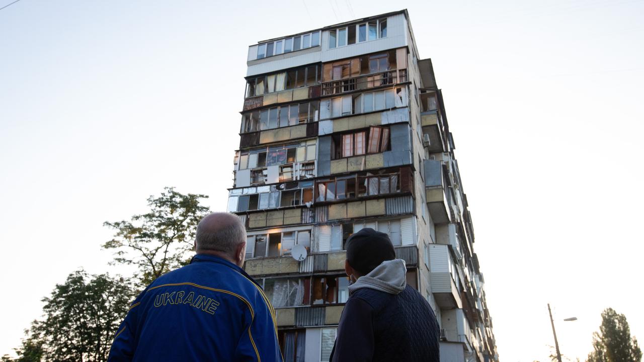 Zwei Männer stehen am Morgen nach den Luftangriffen vor einem zerstörten Haus.