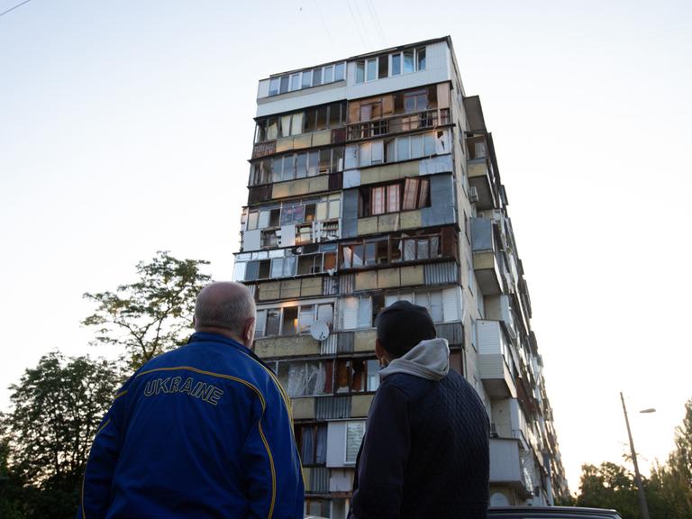 Zwei Männer stehen am Morgen nach den Luftangriffen vor einem zerstörten Haus.
