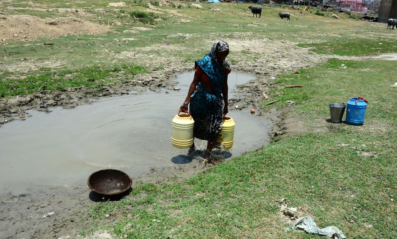Eine Frau trägt einen Behälter voller Wasser nahe einer fast eingetrockneten Wasserstelle in Allahabad. Eine Frau trägt einen Behälter voller Wasser nahe einer fast eingetrockneten Wasserstelle in Allahabad.