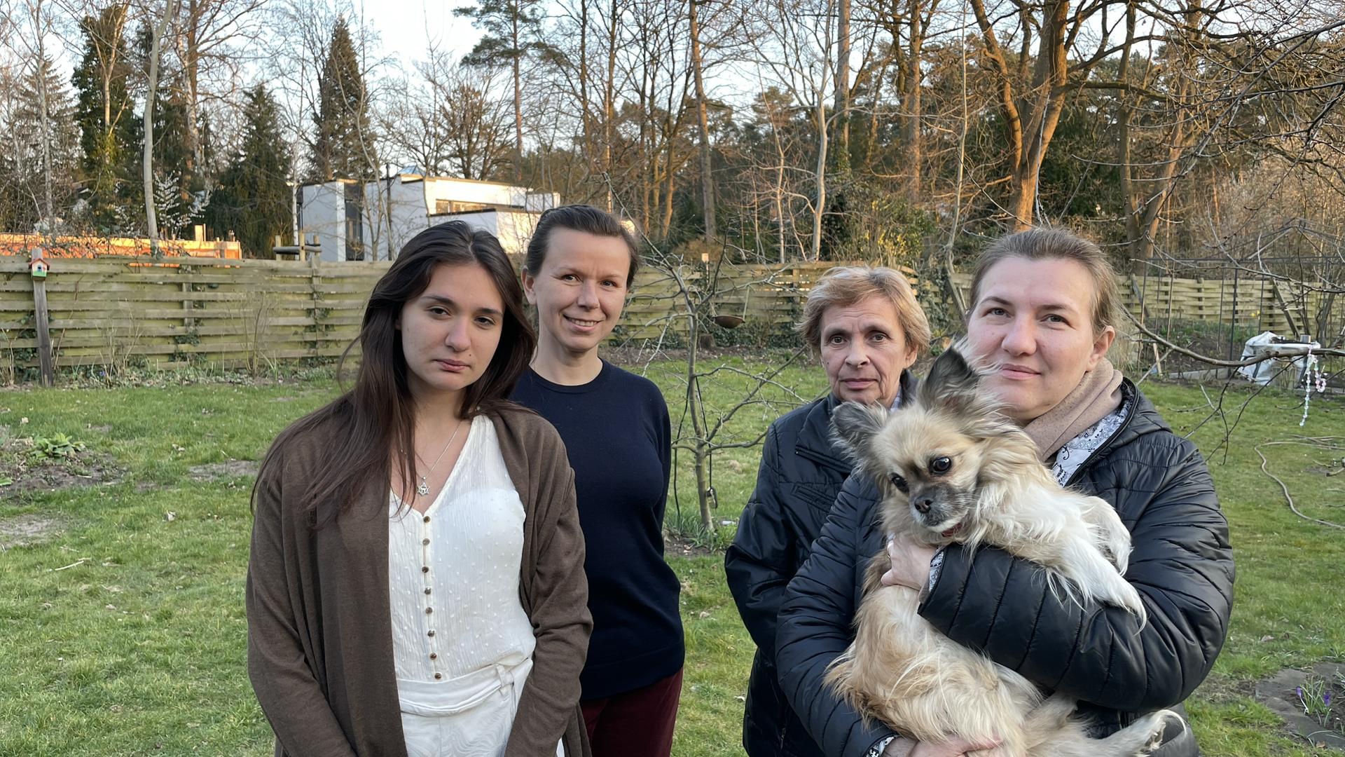 Das Bild zeigt vier Frauen, die auf einer Wiese stehen. Eine hält einen kleinen Hund auf dem Arm. Das Bild zeigt vier Frauen, die auf einer Wiese stehen. Eine hält einen kleinen Hund auf dem Arm.