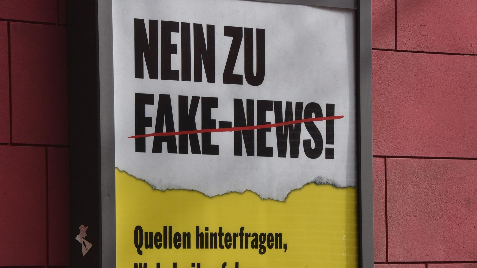 Ein Plakat mit der Aufschrift "Nein zu Fake News" hängt an einer Hauswand in einer Filmkulisse Ein Plakat mit der Aufschrift "Nein zu Fake News" hängt an einer Hauswand in einer Filmkulisse