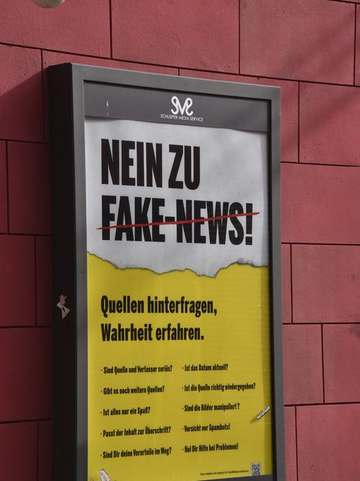 Ein Plakat mit der Aufschrift "Nein zu Fake News" hängt an einer Hauswand in einer Filmkulisse