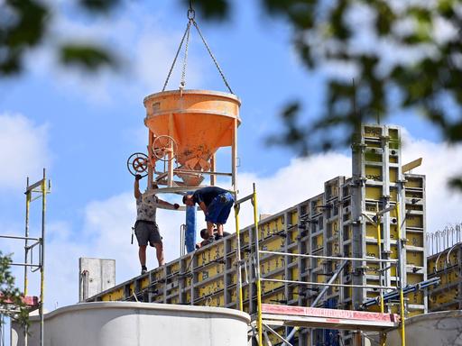 Blick auf Großbaustelle mit Betonkübeln und zwei nicht erkennbaren Bauarbeitern