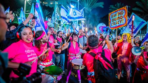Zu sehen sind Demonstranten mit israelischen Flaggen, Trommeln und Trillerpfeifen nachts in Tel Aviv.