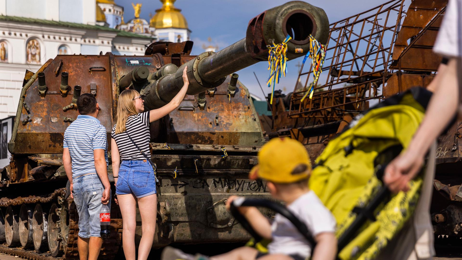 Menschen untersuchen zerstörte russische Panzer in Kiew.
