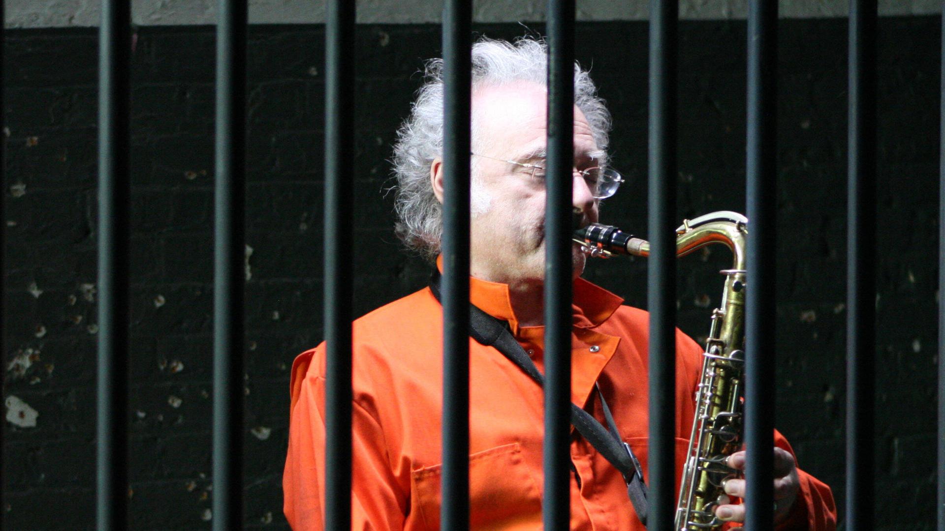 Ein Gefangener spielt hinter Gittern Saxophon. Ein Gefangener spielt hinter Gittern Saxophon.