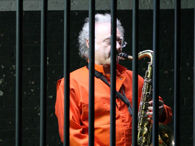 Ein Gefangener spielt hinter Gittern Saxophon.