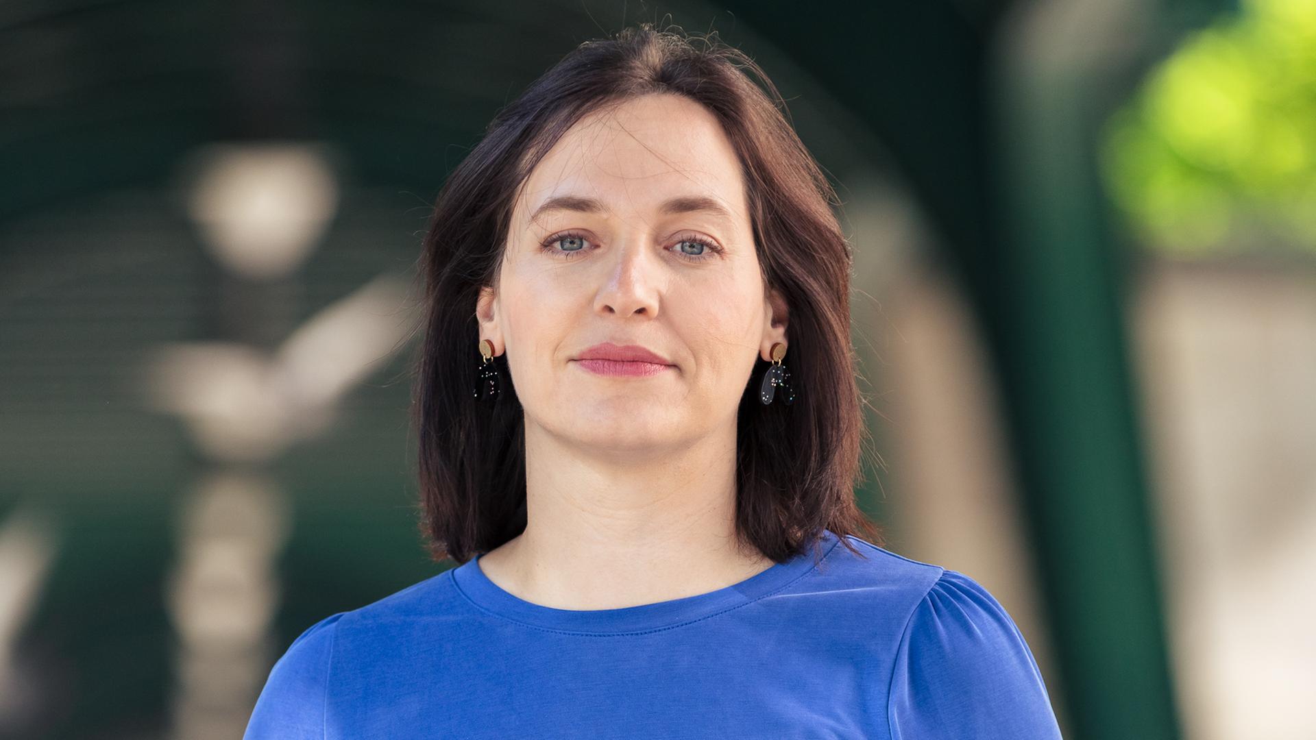 Porträt von Ina Lucas in einem blauen Oberteil und schwarzer Hose Porträt von Ina Lucas in einem blauen Oberteil und schwarzer Hose