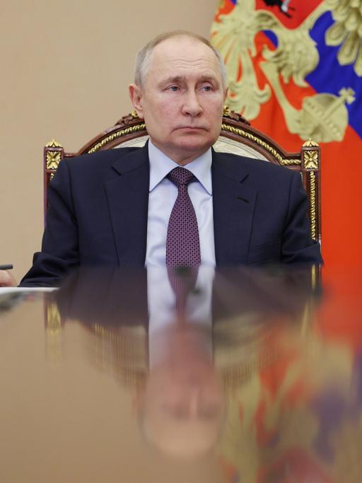 Russlands Präsident Wladimir Putin sitzt an einem Tisch. 