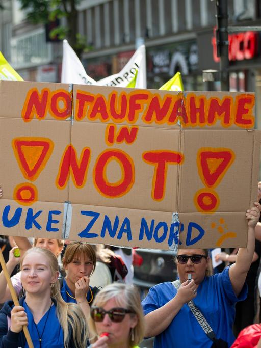 Demonstrantinnen tragen ein Schild mit der Aufschrift "Notaufnahme in Not! UKE ZNA Nord". Zahlreiche Demonstranten aus dem Gesundheitsbereich ziehen durch die Düsseldorfer Innenstadt in Richtung Nordrhein-Westfälischer Landtag. Die Gewerkschaft Verdi hatte zur Demonstration für Unikliniken unter dem Motto "Wir für Euch, ihr für uns" aufgerufen.