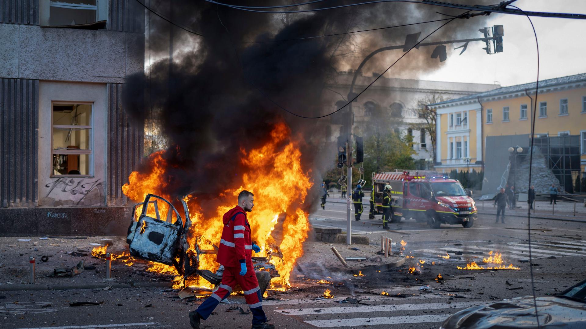 Ein Feuerwehrmann geht an einem brennenden Auto in Kiew in der Ukraine vorbei.