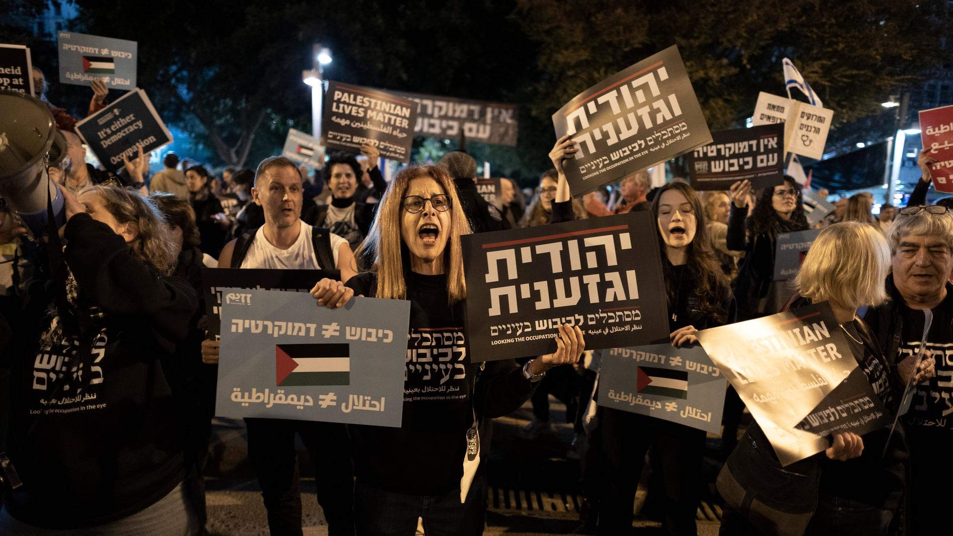 Menschen demonstrieren mit Plakaten während einer Demonstration gegen die neue Regierung. Auf einem steht Palestinian Lives Matter. Menschen demonstrieren mit Plakaten während einer Demonstration gegen die neue Regierung. Auf einem steht Palestinian Lives Matter.