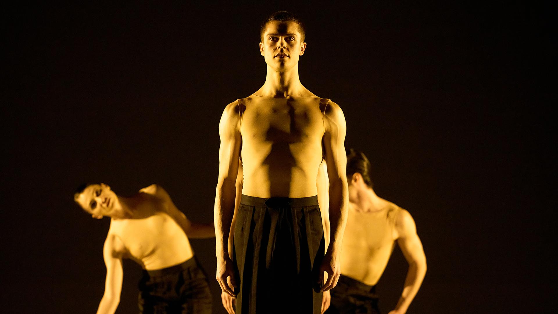 Szene aus dem Ballett "Glaube – Liebe – Hoffnung“ am Staatstheater Hannover: Ein Tänzer steht in der Mitte frontal zum Betrachter, eine Tänzerin und ein weiterer Tänzer seitlich dahinter. Szene aus dem Ballett "Glaube – Liebe – Hoffnung“ am Staatstheater Hannover: Ein Tänzer steht in der Mitte frontal zum Betrachter, eine Tänzerin und ein weiterer Tänzer seitlich dahinter.