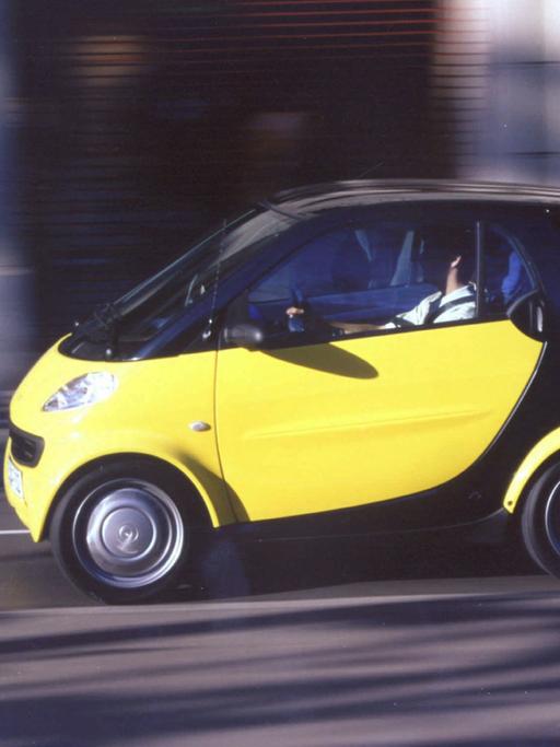 Ein schwarz-gelber Smart fährt auf der Straße.