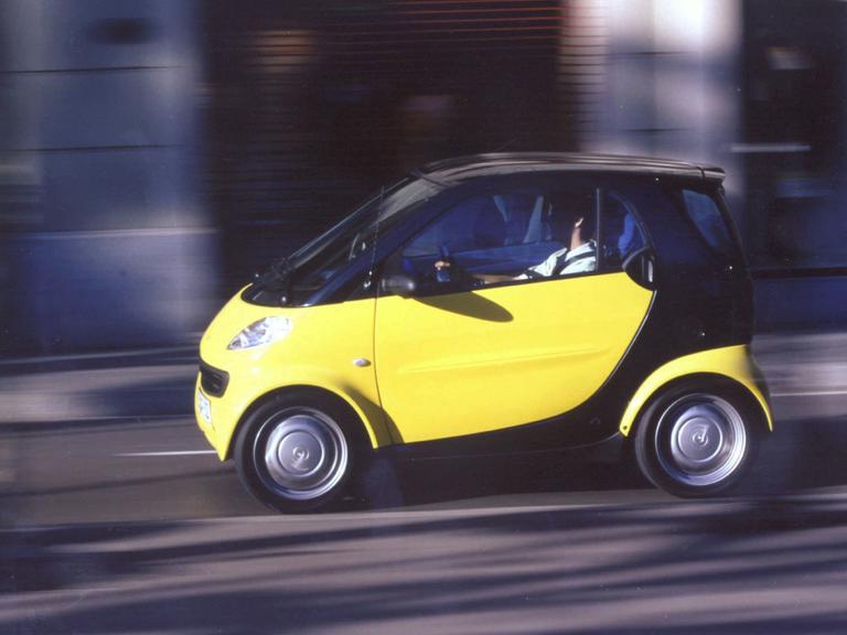 Ein schwarz-gelber Smart fährt auf der Straße.