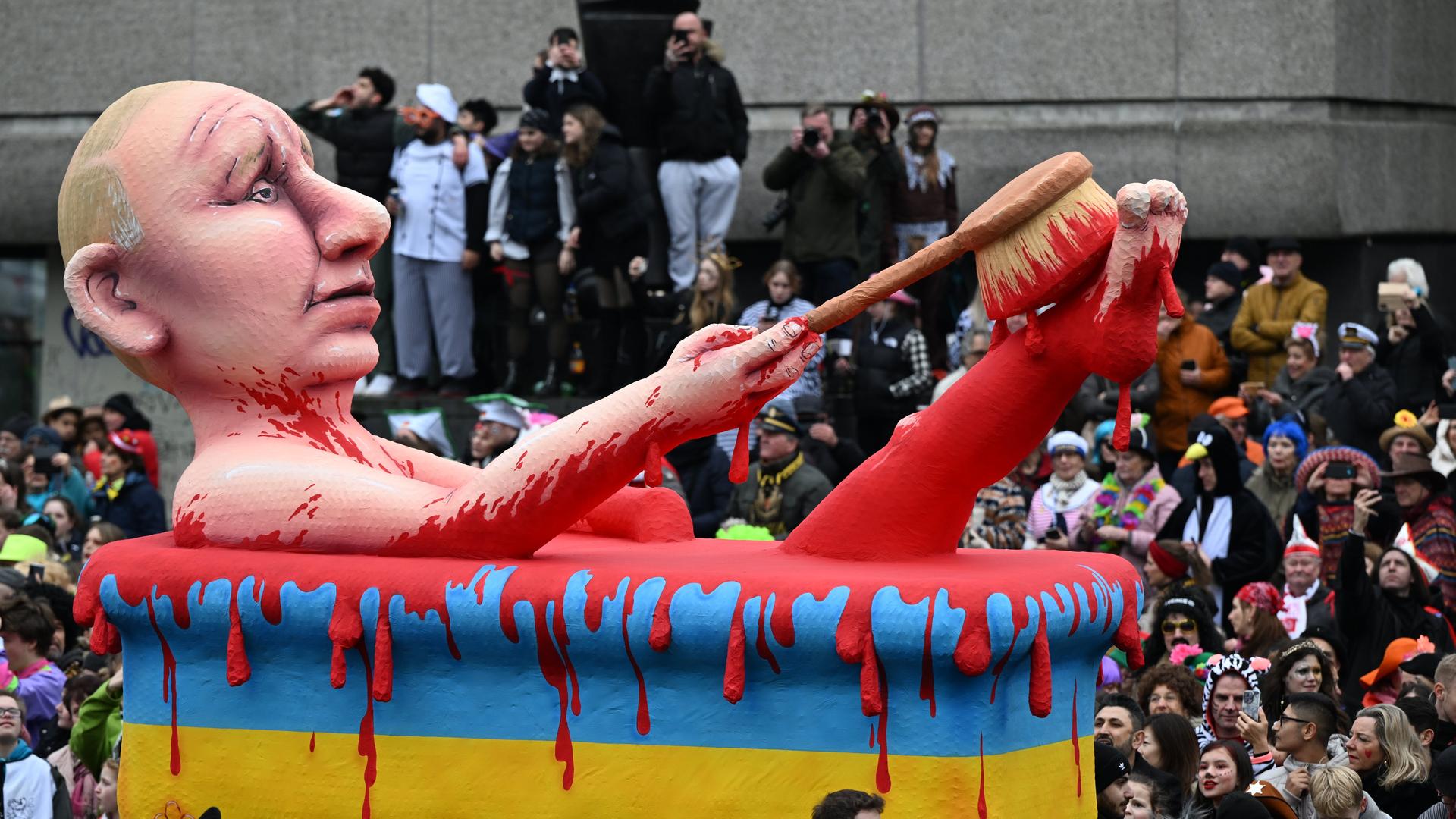 Ein Motto-Wagen zeigt den russischen Präsidenten Putin. Er liegt in einer Bade-Wanne in den ukrainischen National-Farben. Die Wanne ist voll Blut. Ein Motto-Wagen zeigt den russischen Präsidenten Putin. Er liegt in einer Bade-Wanne in den ukrainischen National-Farben. Die Wanne ist voll Blut.