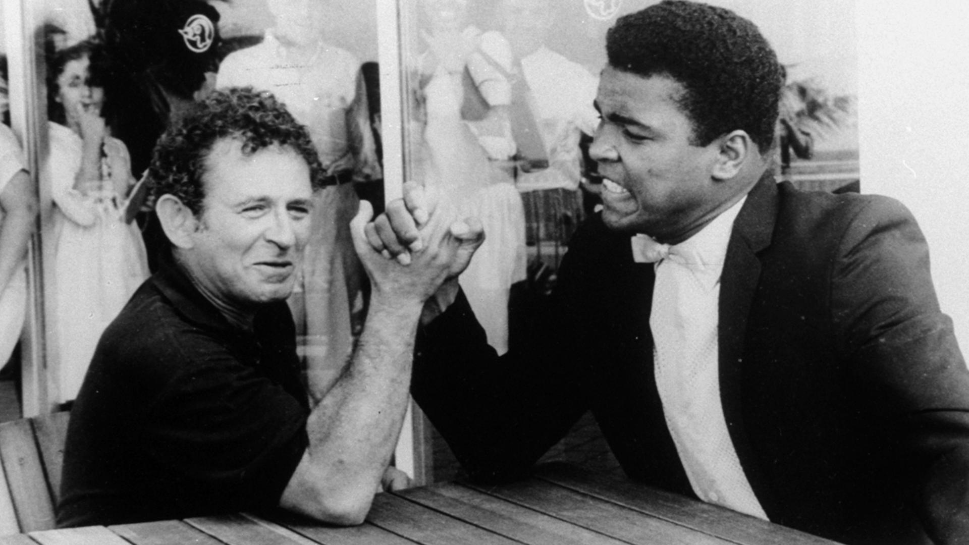 Der  Schriftsteller Norman Mailer (links)  1965 beim Armdrücken mit dem Schwergewichtsweltmeister Muhammad Ali .