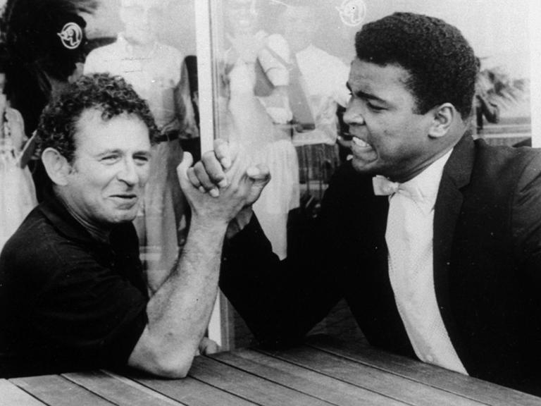 Der  Schriftsteller Norman Mailer (links)  1965 beim Armdrücken mit dem Schwergewichtsweltmeister Muhammad Ali .