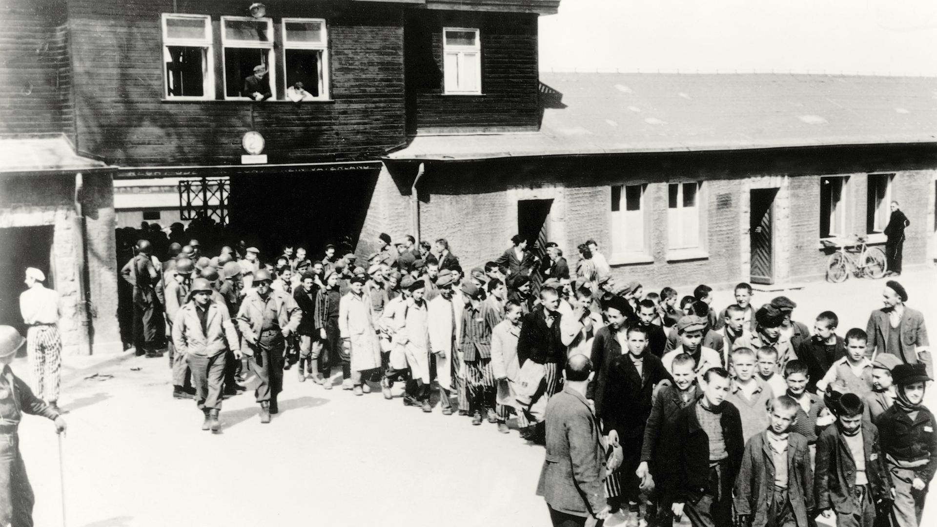 Schwarz-weißes Foto: Menschen verlassen das KZ Buchenwald nach der Befreiung am 11. April 1945. Schwarz-weißes Foto: Menschen verlassen das KZ Buchenwald nach der Befreiung am 11. April 1945.