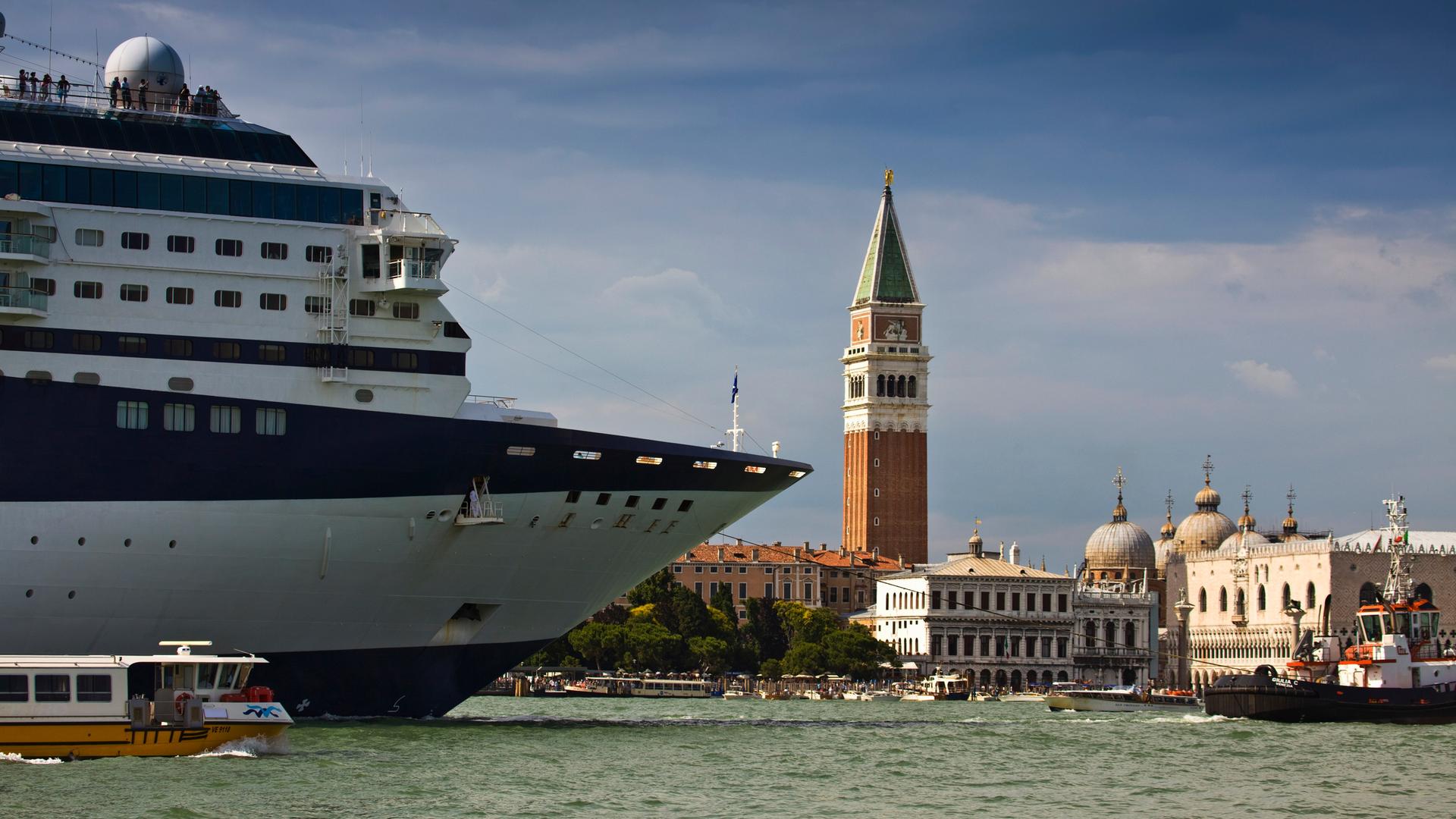 Ein Kreuzfahrtschiff in Venedig. Daneben ein kleines Boot. Ein Kreuzfahrtschiff in Venedig. Daneben ein kleines Boot.