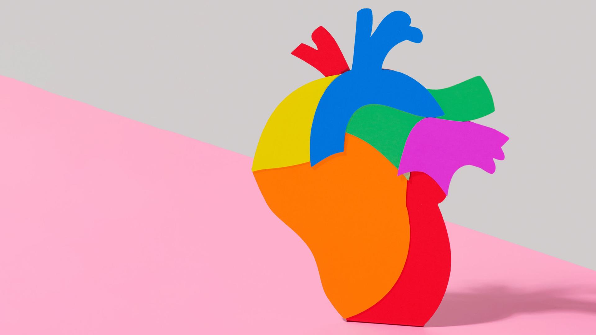 Illustration eines regenbogenfarbenen Herzes vor zweifarbigem Hintergrund.