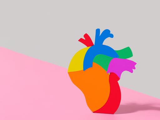 Illustration eines regenbogenfarbenen Herzes vor zweifarbigem Hintergrund.