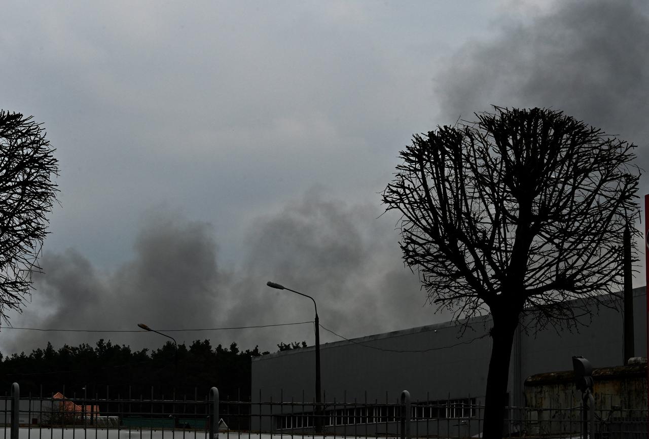 Über Bäumen und einem Gebäude in Kiew steigt Rauch auf.