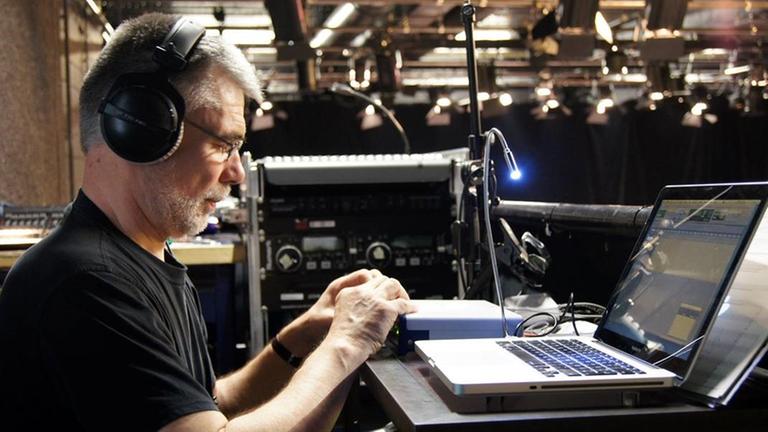 Der Komponist arbeitet mit Kopfhörern an einem Laptop