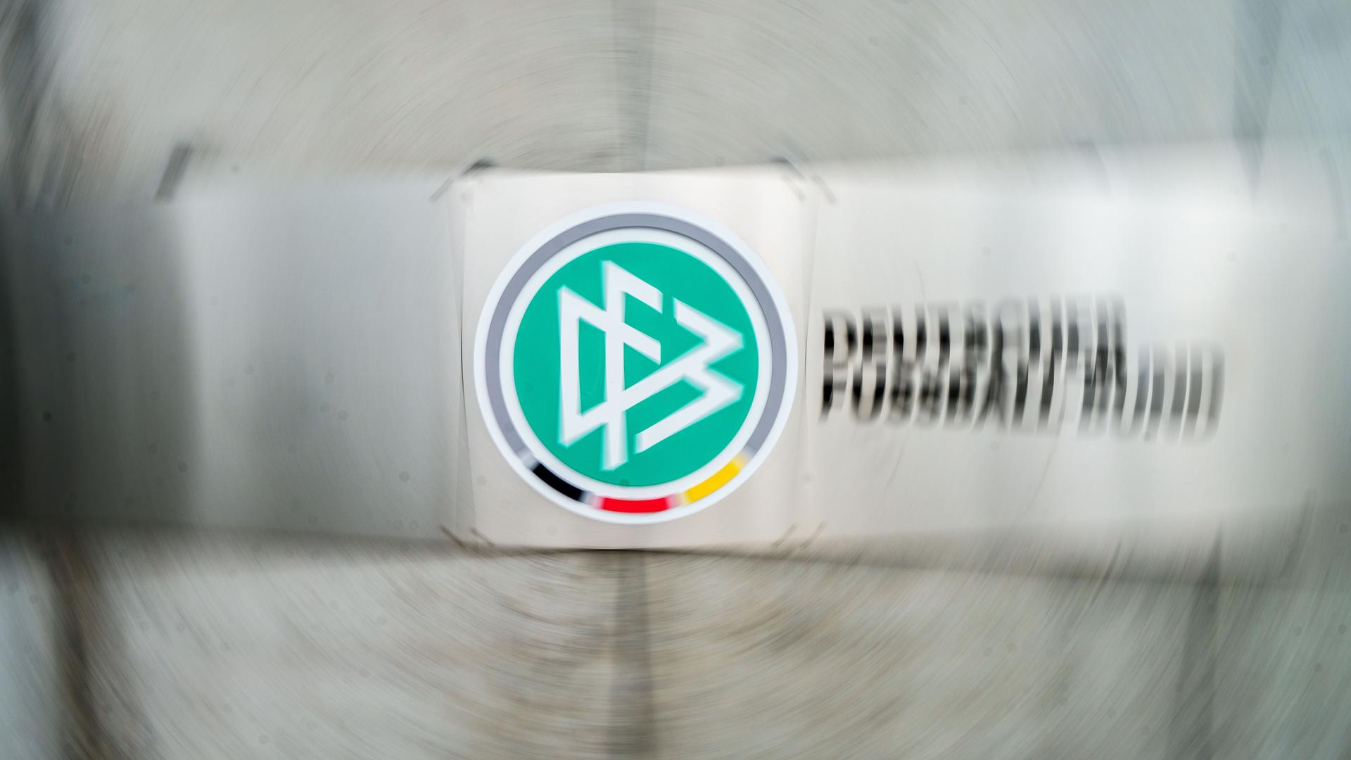 Ein Schild mit dem Logo des Deutschen Fußball-Bundes (DFB) hängt vor dem Eingang zur DFB-Zentrale (Aufnahme mit Dreheffekt). Ein Schild mit dem Logo des Deutschen Fußball-Bundes (DFB) hängt vor dem Eingang zur DFB-Zentrale (Aufnahme mit Dreheffekt).