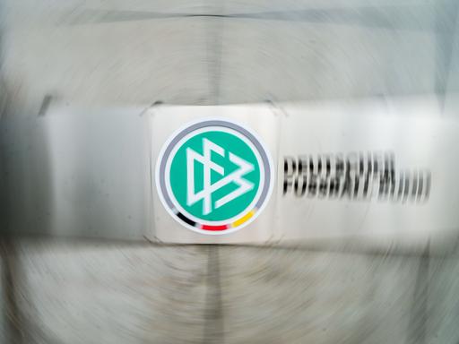 Ein Schild mit dem Logo des Deutschen Fußball-Bundes (DFB) hängt vor dem Eingang zur DFB-Zentrale (Aufnahme mit Dreheffekt). 