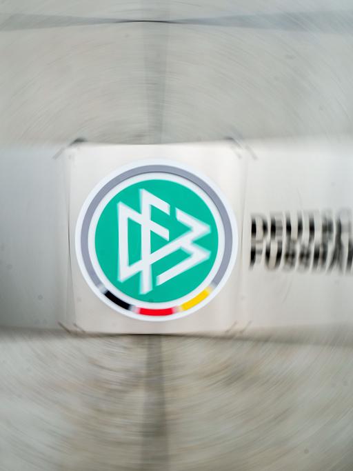 Ein Schild mit dem Logo des Deutschen Fußball-Bundes (DFB) hängt vor dem Eingang zur DFB-Zentrale (Aufnahme mit Dreheffekt). 