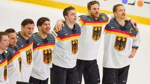 Deutsche Spieler stehen Arm in Arm auf dem Eis.
