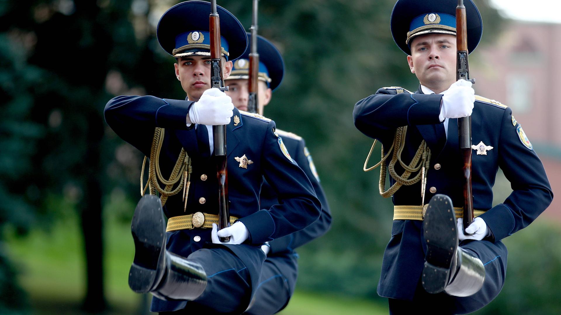 Russische Soldaten in blauer Uniform marschieren im Stechschritt und mit präsentiertem Gewehr. Russische Soldaten in blauer Uniform marschieren im Stechschritt und mit präsentiertem Gewehr.