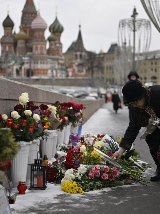 Der russische Oppositionelle Boris Nemzow wurden am 27. Februar 2015 auf einer Brücke erschossen. An seinem Todestag 2023 legt eine Passantin an dem Ort Blumen zum Gedenken an ihn nieder. Dort stehen schon viele Sträuße.