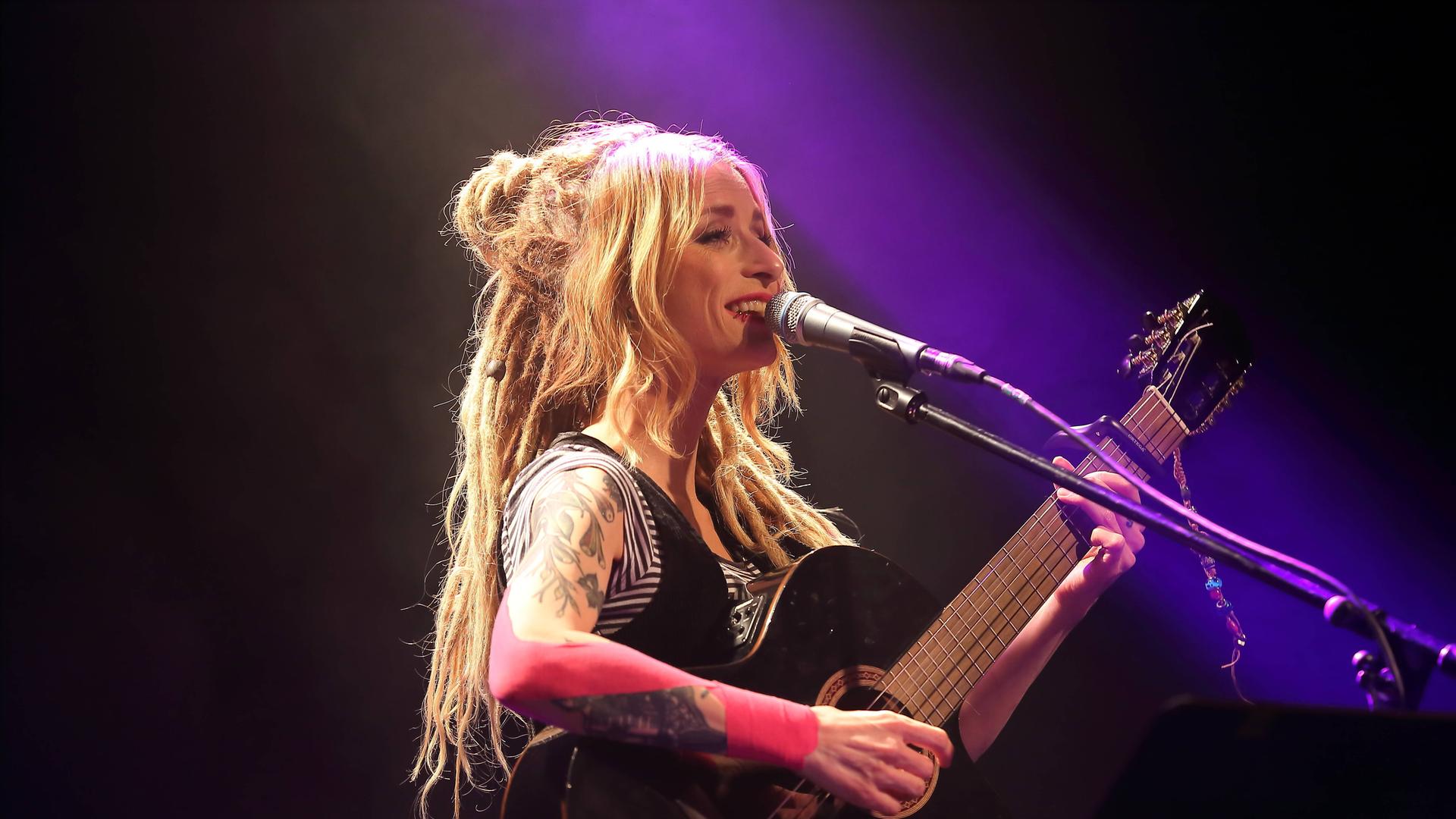 Sarah Lesch steht mit einer Gitarre auf der Bühne. Sarah Lesch steht mit einer Gitarre auf der Bühne.
