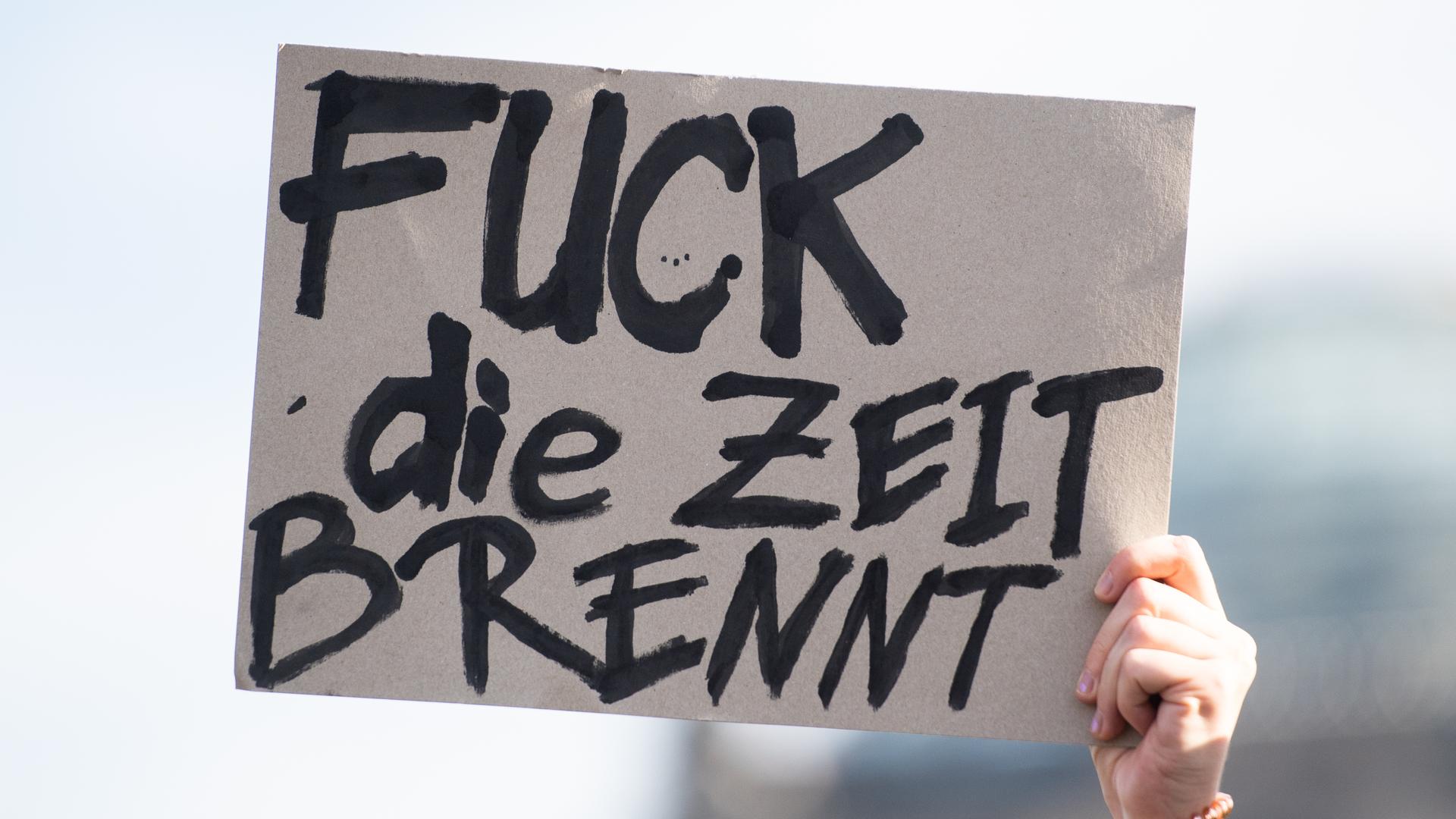 Bei einer Kundgebung von Fridays for Future hält eine Aktivistin ein Plakat mit der Aufschrift "Fuck die Zeit brennt" Bei einer Kundgebung von Fridays for Future hält eine Aktivistin ein Plakat mit der Aufschrift "Fuck die Zeit brennt"