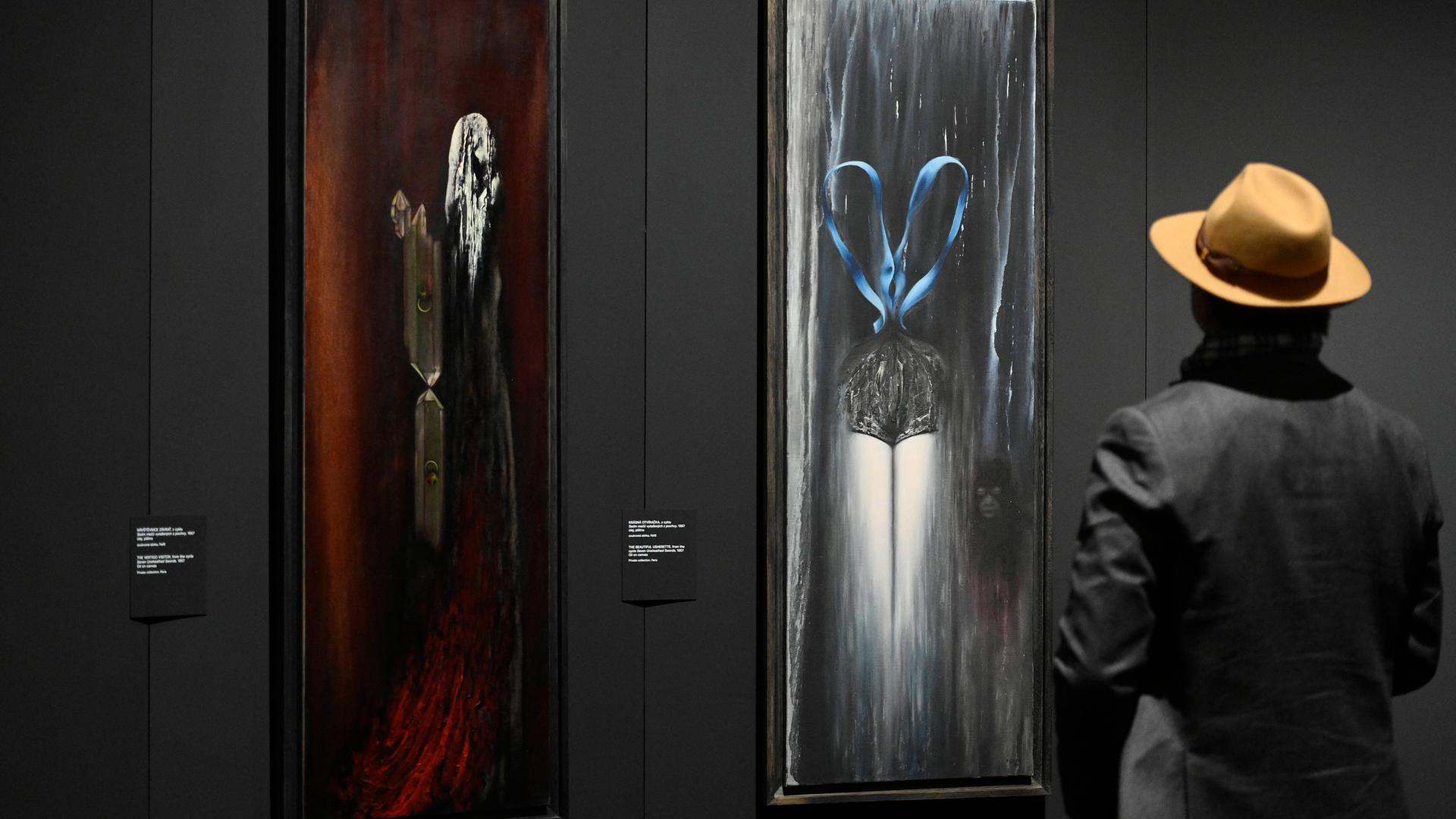 Toyen Gemälde in der "Dreaming Rebel" Ausstellung in der Nationalgalerie in Prag. Eine Person mit Hut betrachtet die Bilder. Toyen Gemälde in der "Dreaming Rebel" Ausstellung in der Nationalgalerie in Prag. Eine Person mit Hut betrachtet die Bilder.