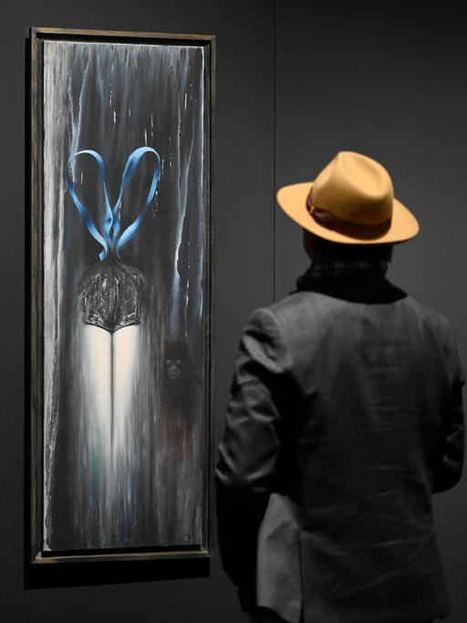 Toyen Gemälde in der "Dreaming Rebel" Ausstellung in der Nationalgalerie in Prag. Eine Person mit Hut betrachtet die Bilder.